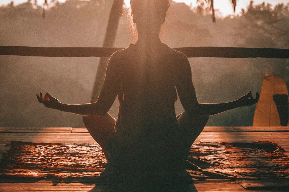 Peaceful sun-drenched morning room with meditation cushion on wood floor and gentle golden sunrise illumination